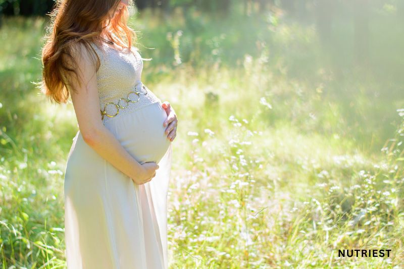 Pregnant woman in nature, representing the power of natural fertility boosters and supplements.