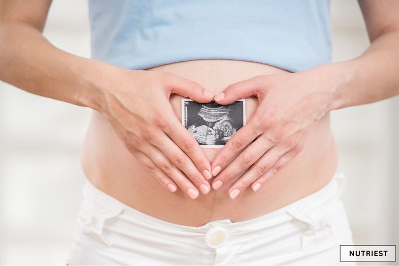 Pregnant woman holding ultrasound photo, symbolising can you take collagen while pregnant